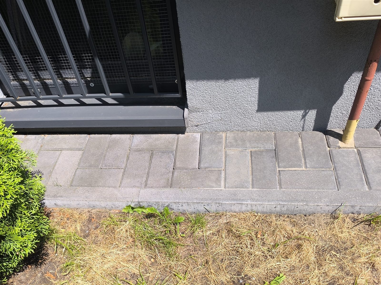 Opaska z kostki brukowej przy elewacji domu